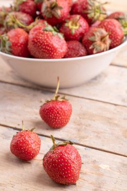 ahşap masa üzerinde plaka üç ham çilek ve birçok çirkin çilek, üst görünümü