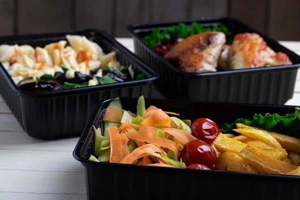 Бизнес-ланч в коробках с едой, жареные куриные крылышки, овощи на пару, тушеное мясо, закрыть и в сторону назад — стоковое фото