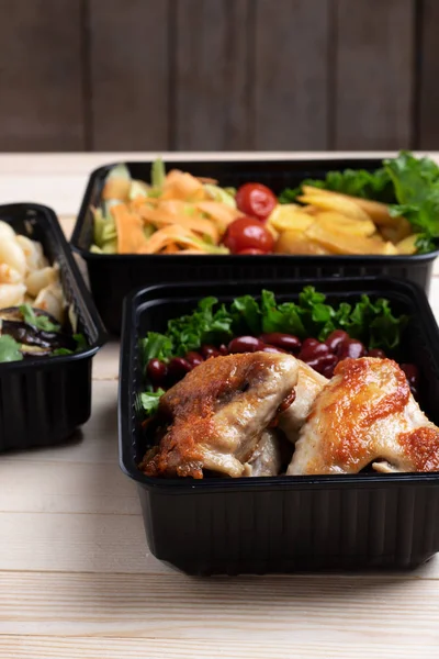 Fried chicken wings with micro greens, stewed vegetables in food containers — Stock Photo, Image