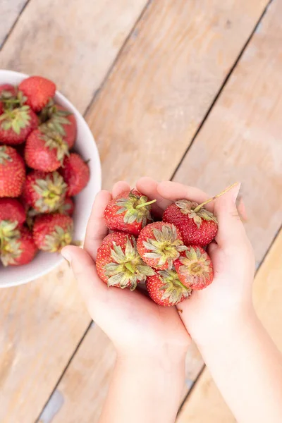 girl holding strawberries in hands, blurred background