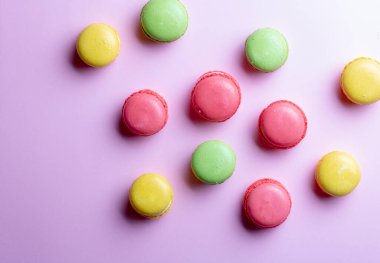 Pembe kağıt üzerinde renkli badem kurabiyeleri, düz yatak. Kimse yok.