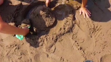 cropped view of children playing with wet sand