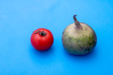 Mavi arka planda kırmızı domatesli siyah turp