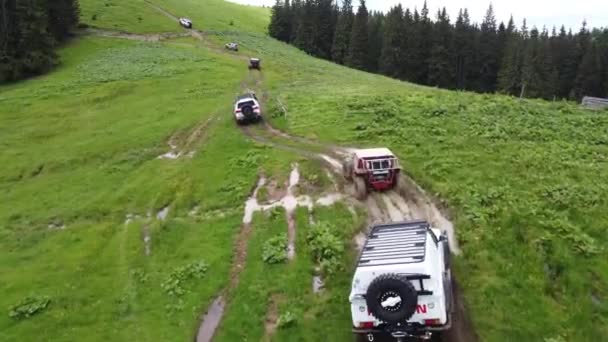 未舗装の道路に沿って山道をいくつかのSuvが走っています 空中風景 — ストック動画