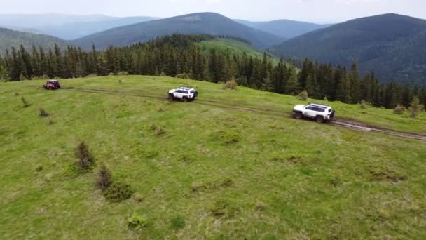 未舗装の道路に沿って山道をいくつかのSuvが走っています 空中風景 — ストック動画