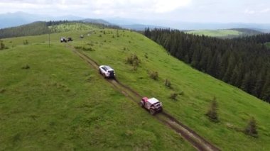 Birkaç SUV toprak bir yol boyunca bir dağ yolu boyunca gidiyor. Hava görünümü.