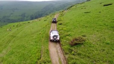 Birkaç SUV toprak bir yol boyunca bir dağ yolu boyunca gidiyor. Hava görünümü. 