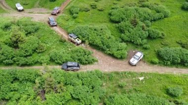 Birkaç SUV toprak bir yol boyunca bir dağ yolu boyunca gidiyor. Hava görünümü