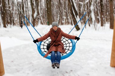 Kahverengi ceketli salıncakta oturan kadın