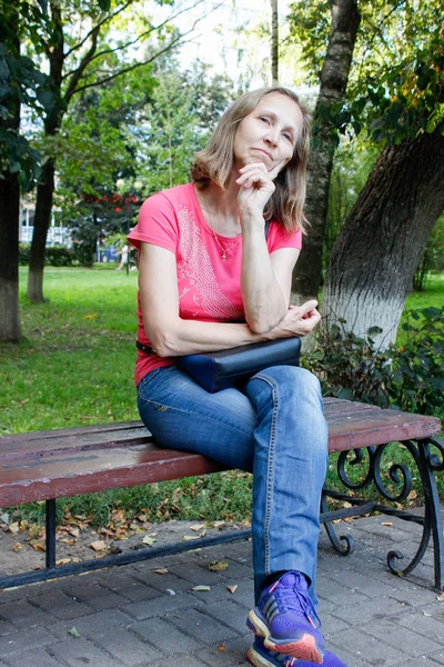 Frau sitzt auf einer Parkbank — Stockfoto