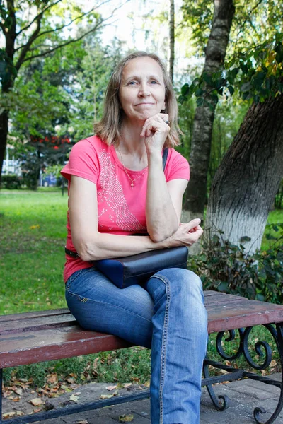 Vrouw zittend op een park bank — Stockfoto