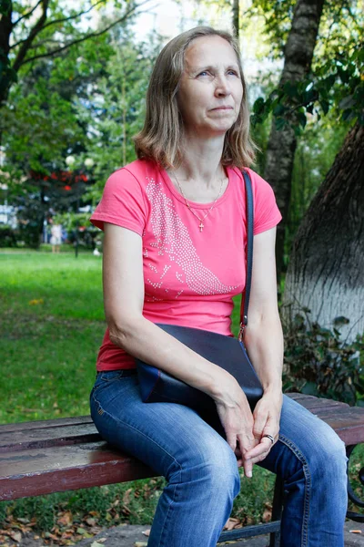 Femme assise sur un banc de parc — Photo