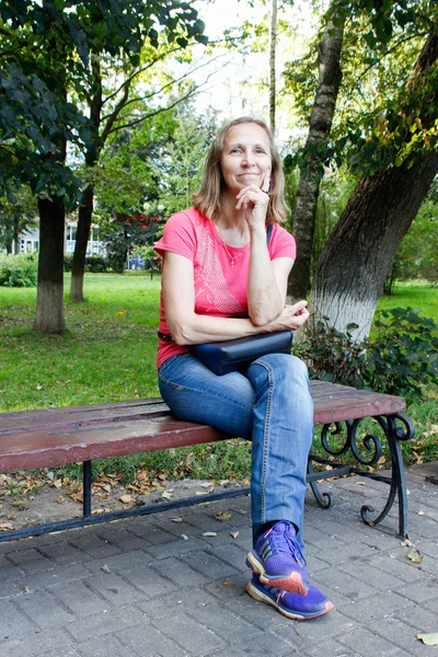 Kobieta siedząca na ławce w parku — Zdjęcie stockowe