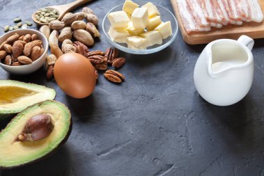 Keto ürün: avokado, tereyağı, pastırma, yumurta, siyah arka plan fındık. Sağlıklı yağlar kavramı