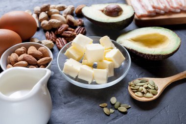 Keto ürün: avokado, tereyağı, pastırma, yumurta, siyah arka plan fındık. Sağlıklı yağlar kavramı