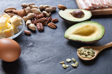 Keto ürün: avokado, tereyağı, pastırma, yumurta, siyah arka plan fındık. Sağlıklı yağlar kavramı