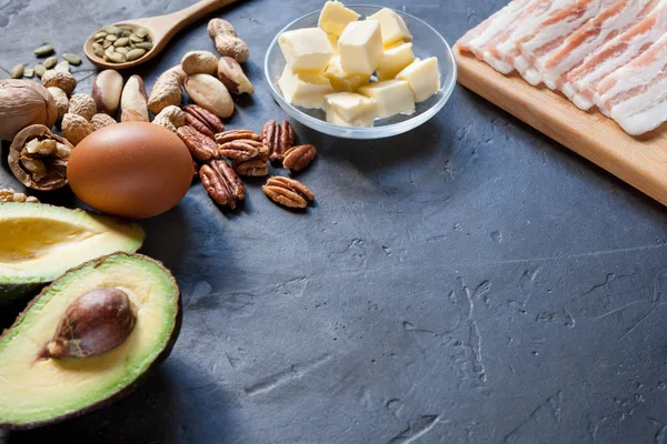 Ketogenic diet food: avocado, nuts, cream, oil, bacon, closeup