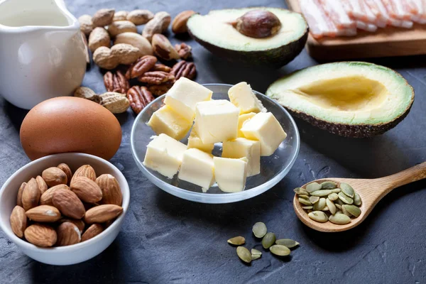 Keto ürün: avokado, tereyağı, pastırma, yumurta, siyah arka plan fındık. Sağlıklı yağlar kavramı