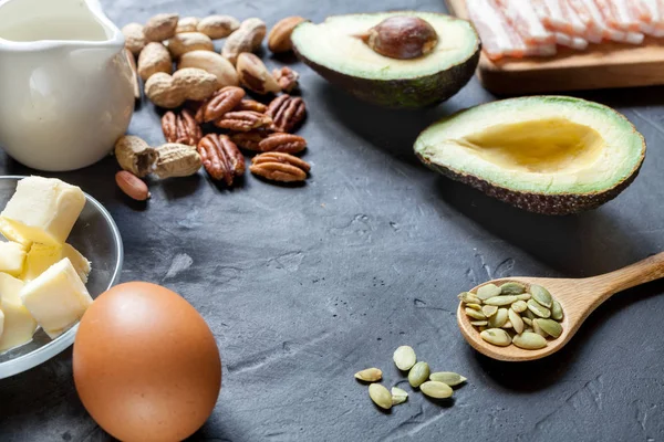 Keto ürün: avokado, tereyağı, pastırma, yumurta, siyah arka plan fındık. Sağlıklı yağlar kavramı