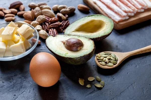 Keto ürün: avokado, tereyağı, pastırma, yumurta, siyah arka plan fındık. Sağlıklı yağlar kavramı