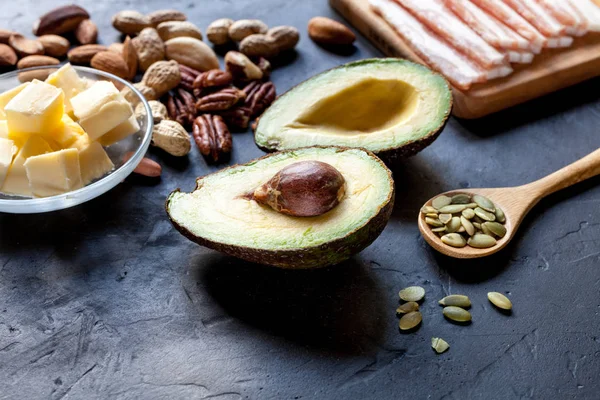 Ketogenic diet food: avocado, nuts, cream, oil, bacon, closeup