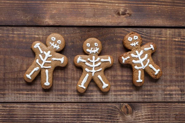 Ahşap masada üç tane iskelet kurabiye var. Cadılar Bayramı konsepti.