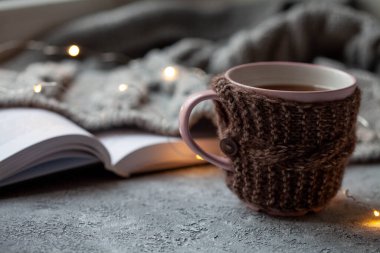 Bir fincan sıcak çay ve gri arkaplan üzerine bir kitap, yakın plan.