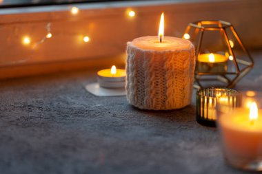 Pencere kenarında birkaç mum var. Hygge konsepti
