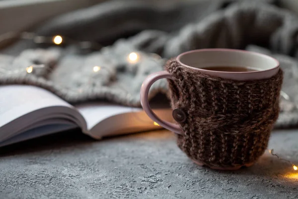 Bir fincan sıcak çay ve gri arkaplan üzerine bir kitap, yakın plan.