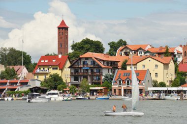 Mikolajki, Poland, July 12: View to city from the lake on July 12, 2020 at Mikolajki, Poland. Mikolajki is a resort town in the Warmian-Masurian Voivodeship in north-eastern Poland. clipart