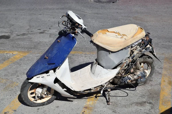 Old, damaged motor scooter at parking