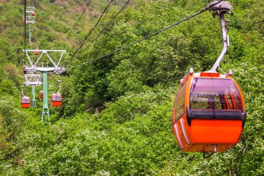 Cab of orange colour of cableway on the background of Mountain landscape clipart