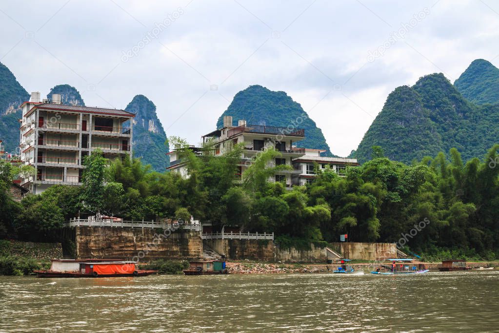 Multi-storey and multi-apartment houses on the scenic shore of the Li River against the backdrop of karst peaks in the Chinese city of Xingping.