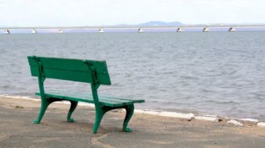 Bir dinlenme park bankında ve bir görünüm De Friz yarımadanın Amur Bay ayında Vladivostok Uzakdoğu şehir genelinde bir düşük su köprüye Sedanka istasyonundan kıyıdan.