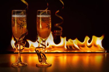 İki bardak köpüklü şampanya altın şeritler parlak alevler Noel ve yeni yıl, rahat bir atmosfer yaratan bokeh arka planı