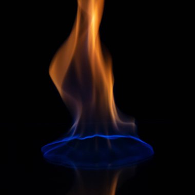 Yanan bir alev parlak siyah bir arka planda parlıyor ve karanlık bir cam yansıtılır.