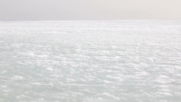 Bakgrund av vit snö och tjällossning under Fjärran Östern vintern och rörlighet för is och slask i havet aktuella mot bakgrund av ett abstrakt landskap. — Stockvideo