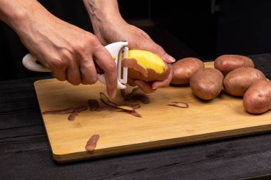 Özel bir bıçak Peeler ile patates temizleme süreci. Aşçı Patates kızartmak veya kaynatmak için hazırlar