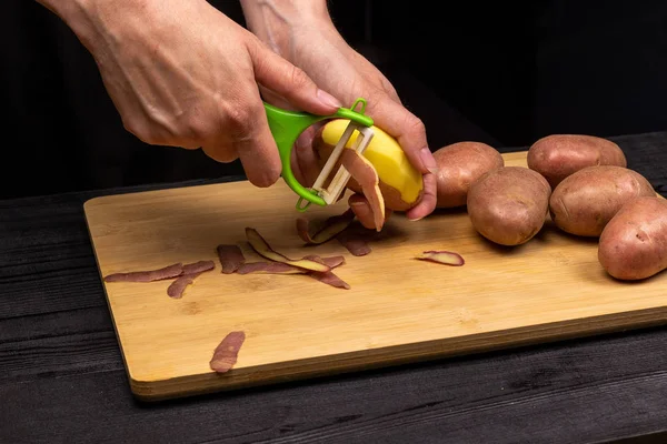 Das Reinigen der Kartoffeln mit einem speziellen Messerschäler. der Koch bereitet Kartoffeln zum Braten oder Kochen zu — Stockfoto