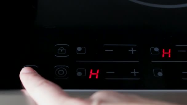 A woman presses a finger, including and setting up an electronic digital panel of a modern electric stove before starting cooking — Stock Video