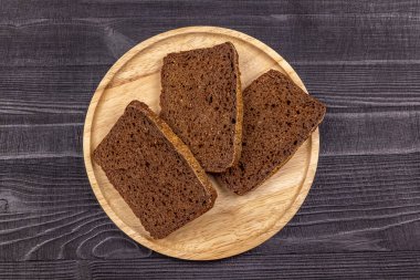 Ahşap servis tabağına çavdar unu siyah ekmek parçaları ve siyah rustik arka plan