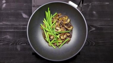 Sarımsak filizi ve tavuk fileto ile mantar dilimlenmiş parçalar bir wok tavada yağda kızartılır. Ev yapımı tarifine göre mantar ve kızarmış erişte ile yemek pişirme süreci. Yakın