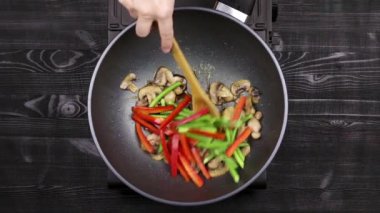 Biber ve sarımsak filizi ile sebzeler ve tavuk fileto ile dilimlenmiş mantar bir wok tavada kızartılır. Ev yapımı tarife göre champignons ve kızarmış erişte ile pişirme. Yakın.