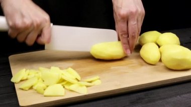 Dişi şefin elleri kızartma kısık veya güveç için patates dilimleri kesin. Ev yapımı tarifi pişirme sürecinin bir parçası.