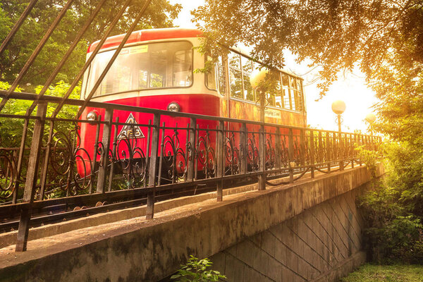The Red Car of the Funicular rises in the bright sunlight of an evening sunset in the capital of the Russian Far East, Vladivostok