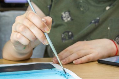 Resim yapmak için fırçayla çalışan çocuklar suluboya resimler çizerler..