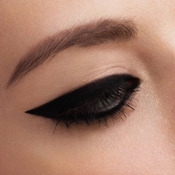 Cosmetics & make-up. Beautiful female eye with sexy black liner makeup. Fashion big arrow shape on woman\'s eyelid. Chic evening make-up