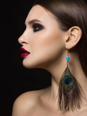 Kırmızı ruj ve siyah dumanlı göz farı Moda tavus kuşu tüyü küpe ölümcül makyaj vurgular bir ryunet kadının muhteşem yüz özellikleri ile güzelliği yakın çekim portre sihir ekler