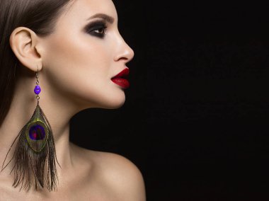 Kırmızı ruj ve siyah dumanlı göz farı Moda tavus kuşu tüyü küpe ölümcül makyaj vurgular bir ryunet kadının muhteşem yüz özellikleri ile güzelliği yakın çekim portre sihir ekler