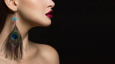 Kırmızı ruj ve moda tavus kuşu tüyü küpe ölümcül makyaj vurgulayan bir ryunette kadının muhteşem yüz özellikleri, güzelliği bir yakın çekim portre sihir görüntüye ekler.